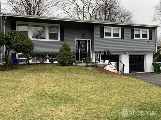 bi-level home featuring aphalt driveway, a garage, and a front lawn