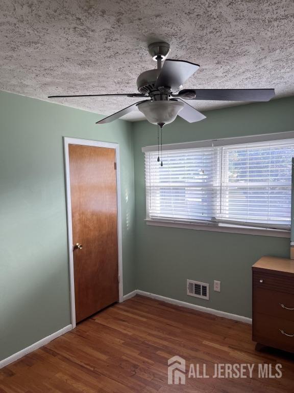 unfurnished bedroom with a closet, visible vents, baseboards, and wood finished floors