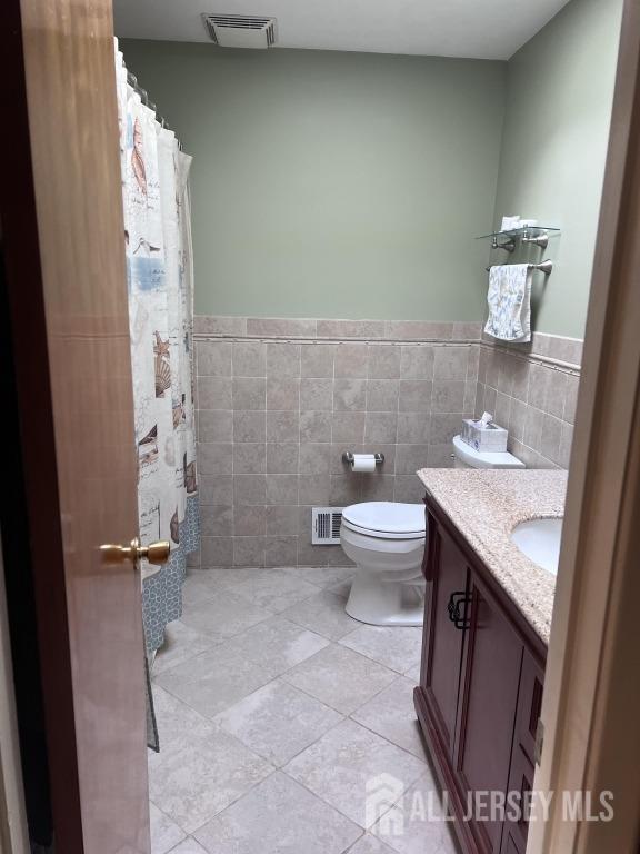 bathroom with vanity, tile walls, and visible vents