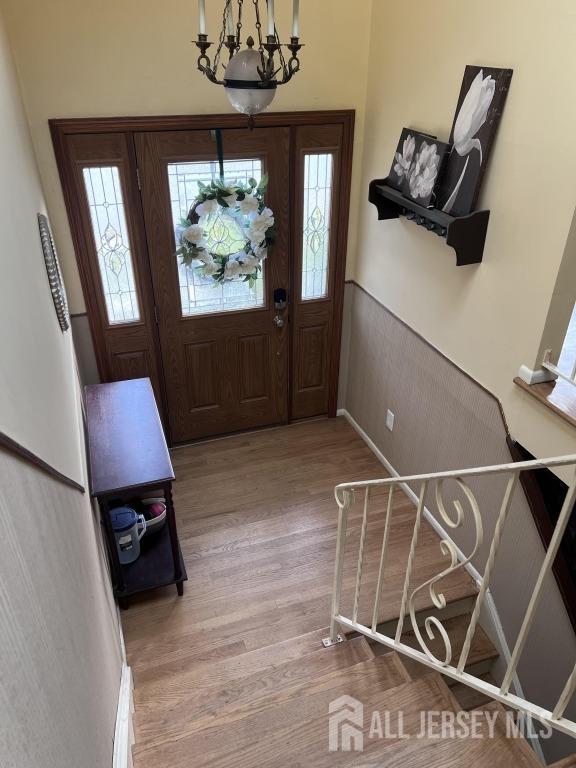 foyer with plenty of natural light, an inviting chandelier, and hardwood / wood-style flooring