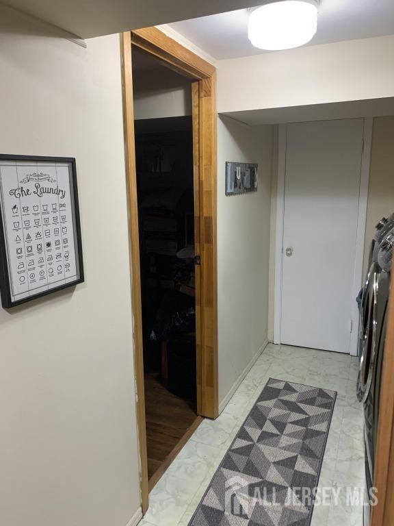 hall with marble finish floor, washer / clothes dryer, and baseboards