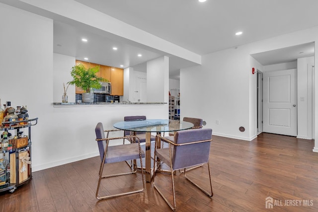 dining area featuring baseboards, dark wood finished floors, and recessed lighting