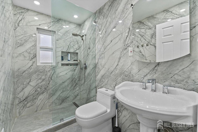 bathroom with tiled shower, toilet, tile walls, and sink