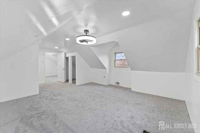 additional living space featuring light colored carpet and vaulted ceiling