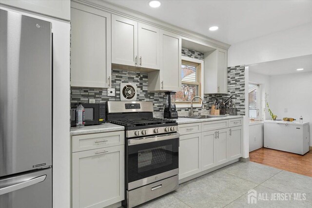 kitchen featuring white cabinets, sink, stainless steel appliances, and tasteful backsplash