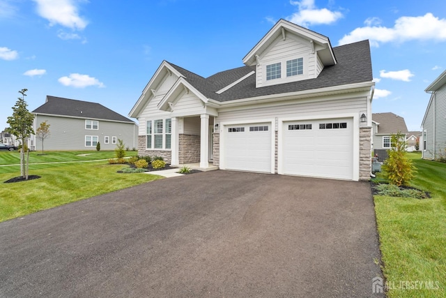 view of front of house featuring driveway, stone siding, a garage, and a front lawn