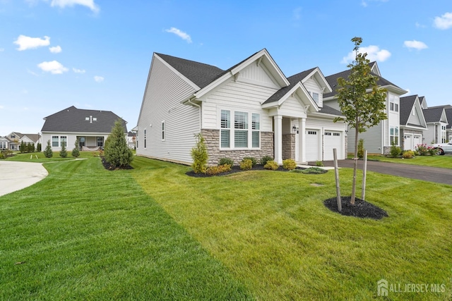 view of front of house with a garage, driveway, stone siding, a residential view, and a front yard