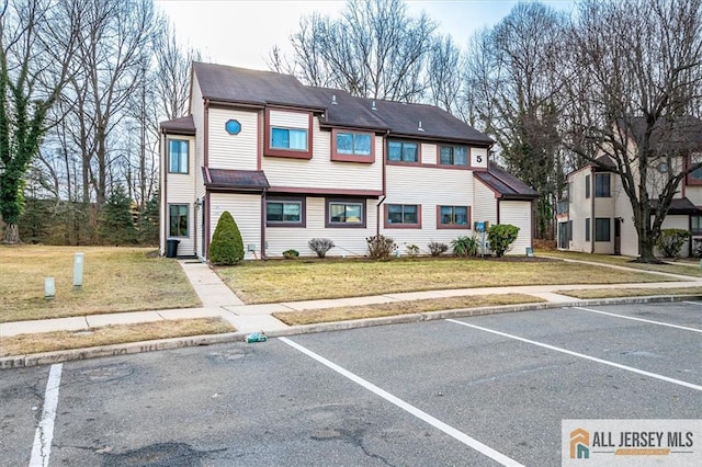 view of front of house featuring uncovered parking and a front yard