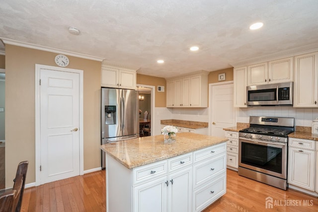 8 Appletree Ln, East Brunswick, NJ 08816 - kitchen featuring stainless steel appliances, backsplash, light wood-style flooring, light stone counters, and a kitchen island