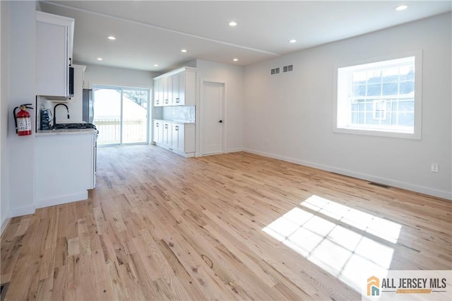 unfurnished living room with sink and light hardwood / wood-style floors