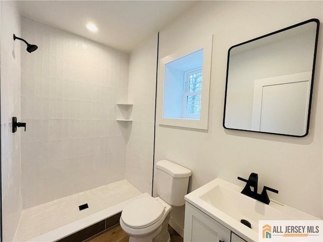 bathroom featuring vanity, tiled shower, and toilet