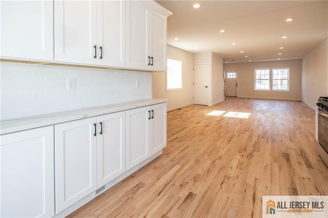 interior space featuring light hardwood / wood-style flooring, a wealth of natural light, tasteful backsplash, and white cabinets