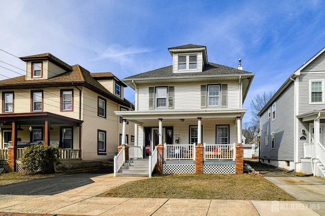 american foursquare style home with a shingled roof and a porch