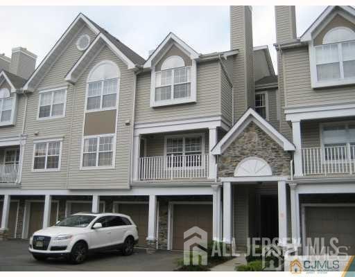 view of property featuring driveway, a chimney, and an attached garage