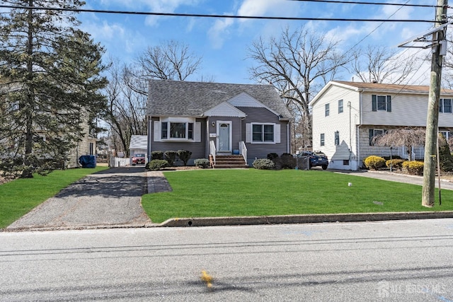 view of front of property with a shingled roof, a front lawn, and aphalt driveway