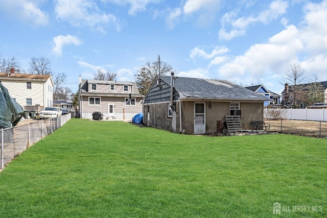 back of property with a fenced backyard, a lawn, and stucco siding