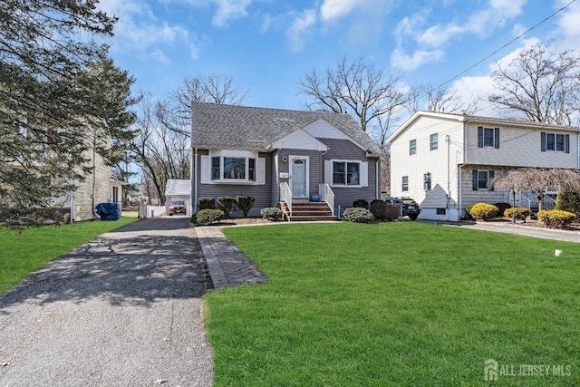 view of front of property featuring driveway, a front lawn, and a shingled roof