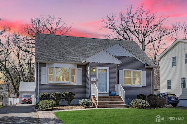 view of front of property featuring an outbuilding, roof with shingles, a yard, and entry steps