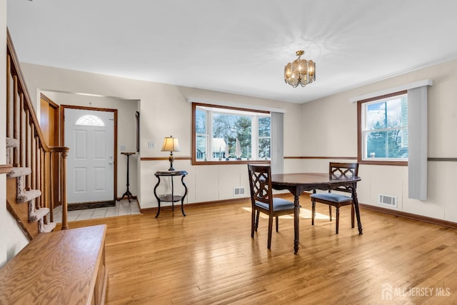 dining room with a healthy amount of sunlight, visible vents, light wood-style flooring, and stairs