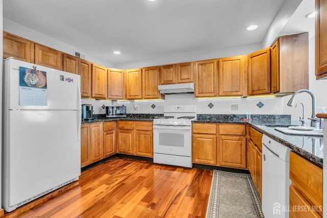 kitchen featuring visible vents, light wood-style floors, a sink, white appliances, and under cabinet range hood