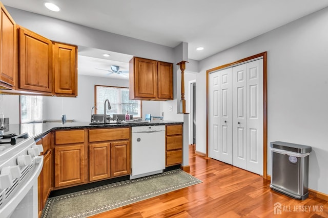 kitchen featuring recessed lighting, white appliances, a sink, brown cabinets, and light wood finished floors