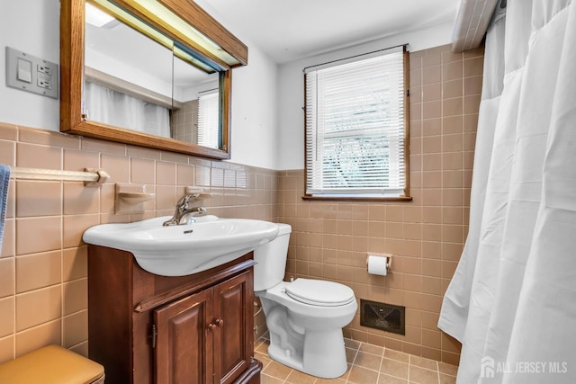 bathroom featuring tile walls, toilet, wainscoting, vanity, and tile patterned floors