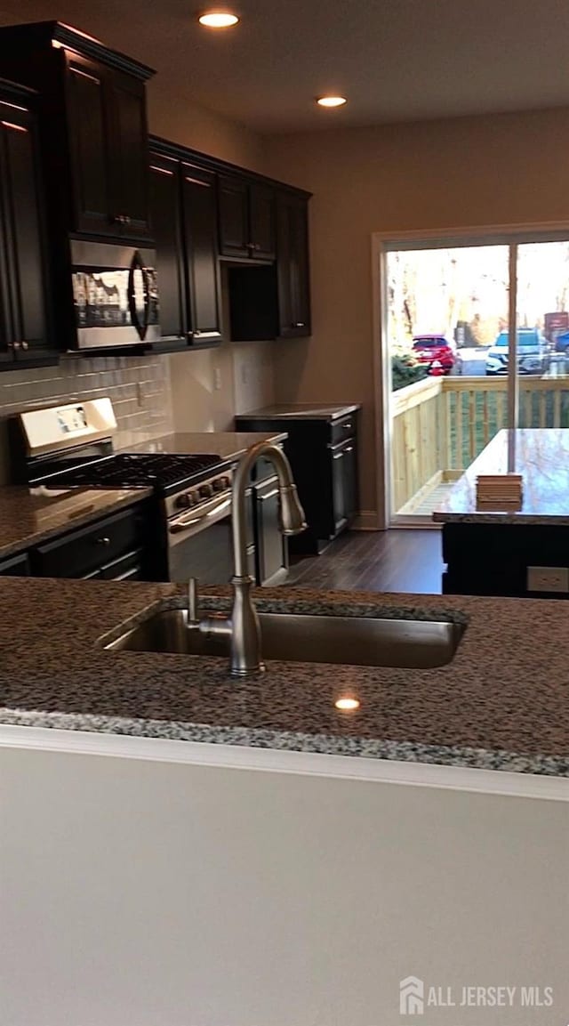 kitchen with backsplash, sink, stainless steel appliances, and dark brown cabinets