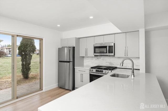 511 Bradley Ct, South Brunswick, NJ 08540 - kitchen featuring stainless steel appliances, a sink, light wood-style floors, backsplash, and light countertops