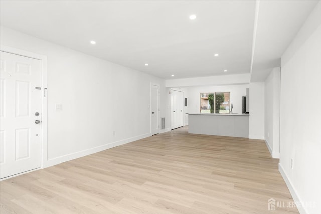 511 Bradley Ct, South Brunswick, NJ 08540 - unfurnished living room with recessed lighting, light wood finished floors, visible vents, a sink, and baseboards