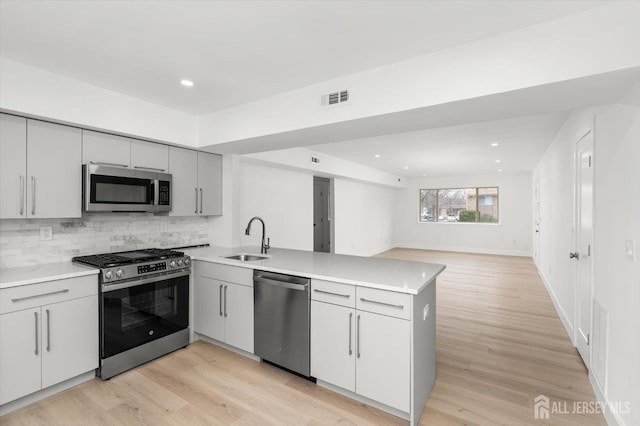 511 Bradley Ct, South Brunswick, NJ 08540 - kitchen featuring stainless steel appliances, a peninsula, a sink, visible vents, and light wood-style floors