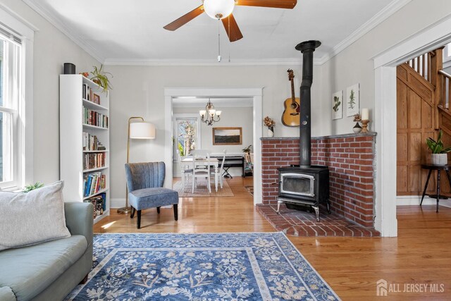 31 Riva Ave, Milltown, NJ 08850 - living area with a wood stove, wood finished floors, a ceiling fan, crown molding, and a chandelier