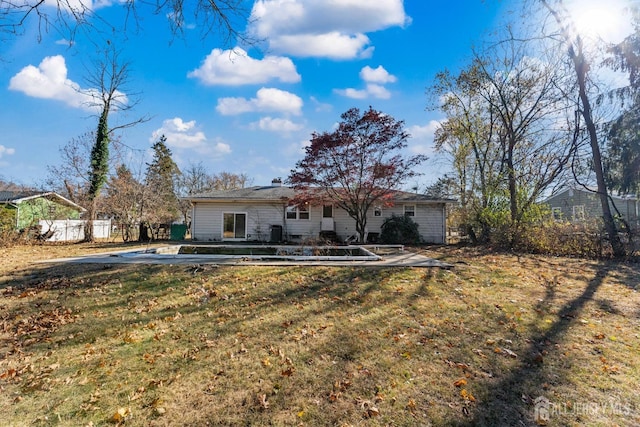 rear view of house featuring a lawn and fence