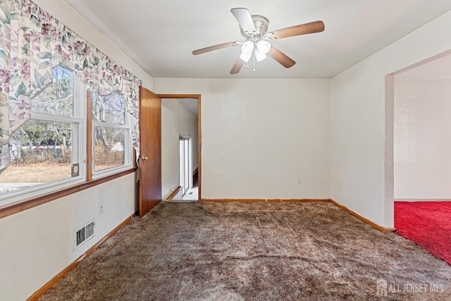 carpeted empty room featuring baseboards, visible vents, and a ceiling fan