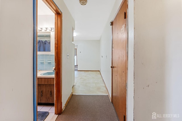 hall with a sink and baseboards