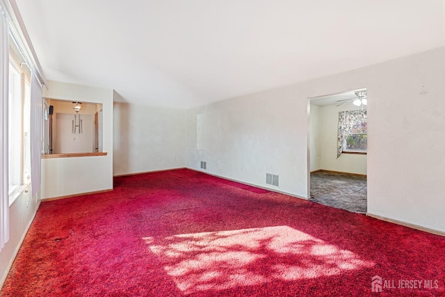 unfurnished room featuring lofted ceiling, carpet flooring, visible vents, and baseboards