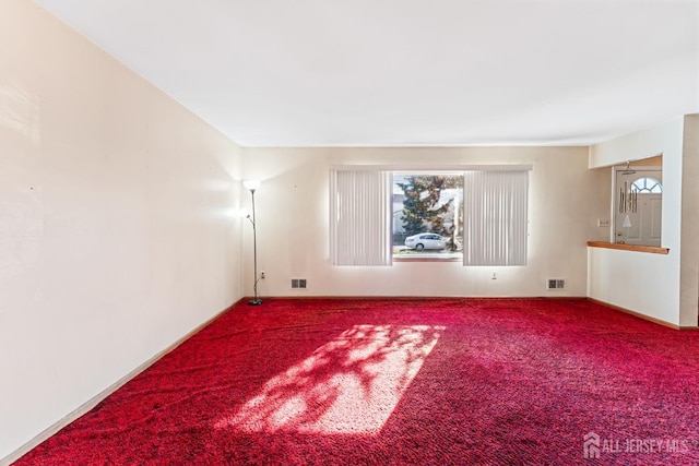 carpeted empty room with a healthy amount of sunlight and visible vents