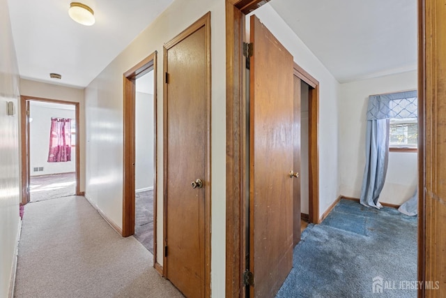 hall with carpet flooring, visible vents, and baseboards