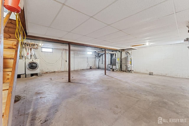 unfinished basement featuring separate washer and dryer, gas water heater, a paneled ceiling, and heating unit