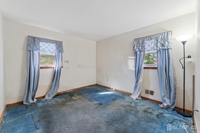 empty room with a healthy amount of sunlight, carpet, visible vents, and baseboards