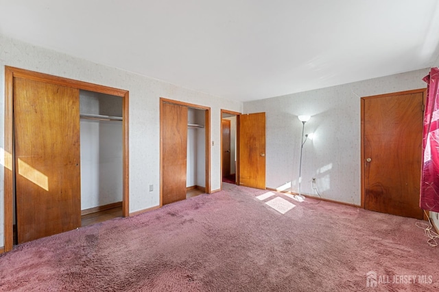 unfurnished bedroom with light carpet and multiple closets