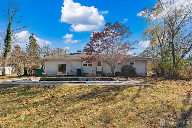 rear view of property featuring a chimney, central AC unit, fence, and a lawn