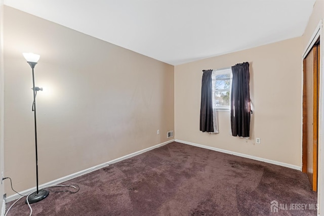 unfurnished bedroom featuring baseboards, visible vents, dark carpet, and a closet