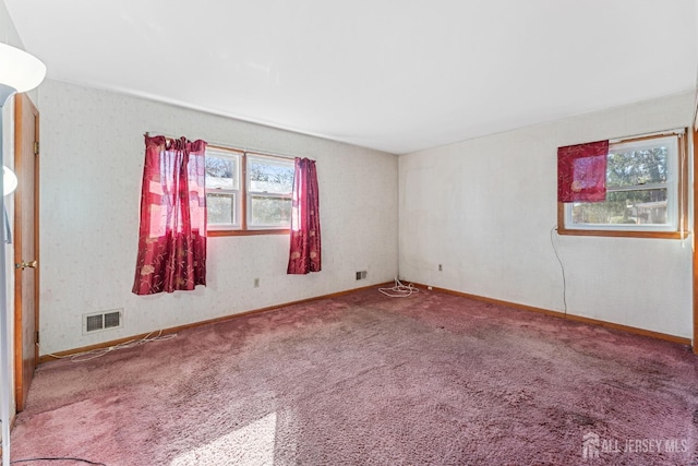 spare room featuring carpet, a healthy amount of sunlight, and visible vents