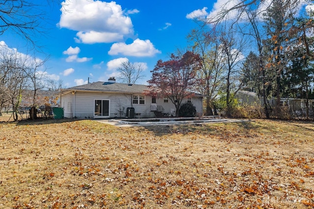 back of house with a patio, a lawn, a chimney, and fence