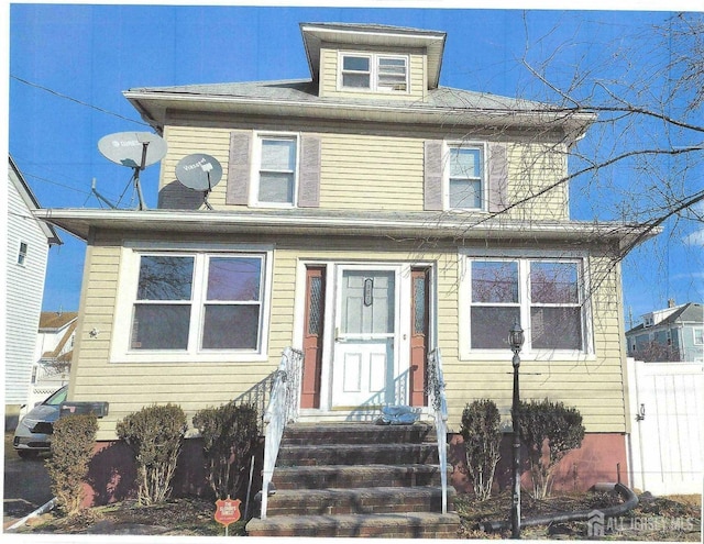 american foursquare style home featuring entry steps and fence