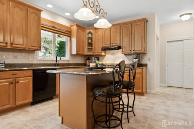 kitchen with black dishwasher, a kitchen breakfast bar, dark stone counters, pendant lighting, and a center island