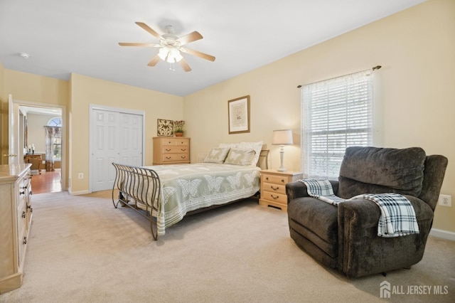 carpeted bedroom with ceiling fan and a closet