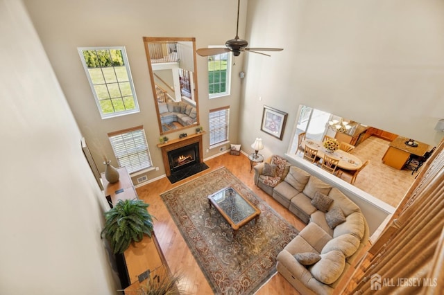 living room with ceiling fan, hardwood / wood-style flooring, and a towering ceiling