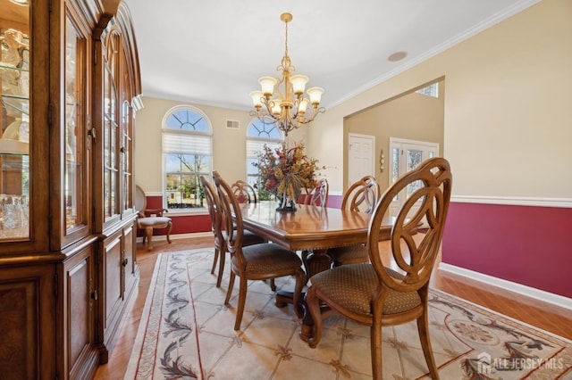 dining space with a notable chandelier, crown molding, and light hardwood / wood-style flooring