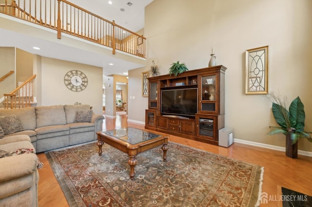 living room featuring a towering ceiling and hardwood / wood-style flooring